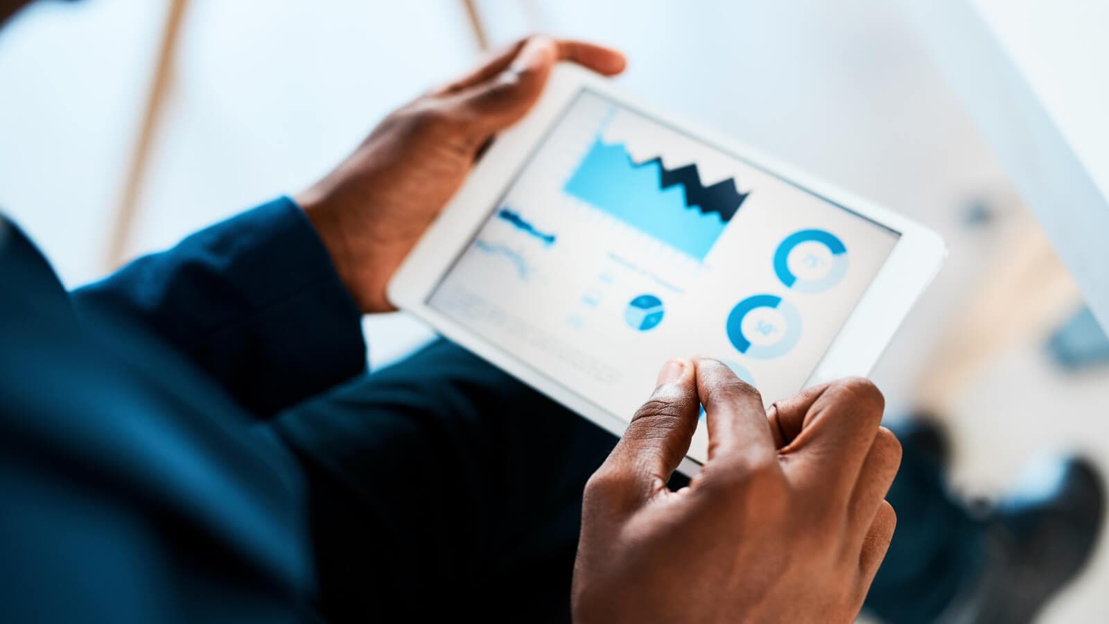 two hands holding a tablet with charts