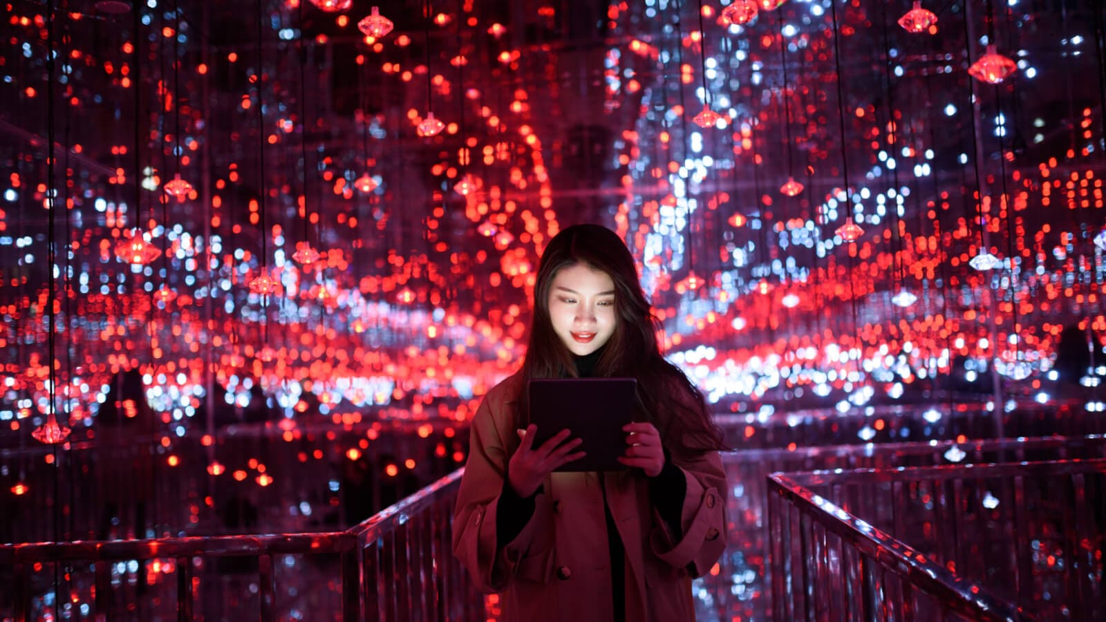 Young woman in front of lights using tablet