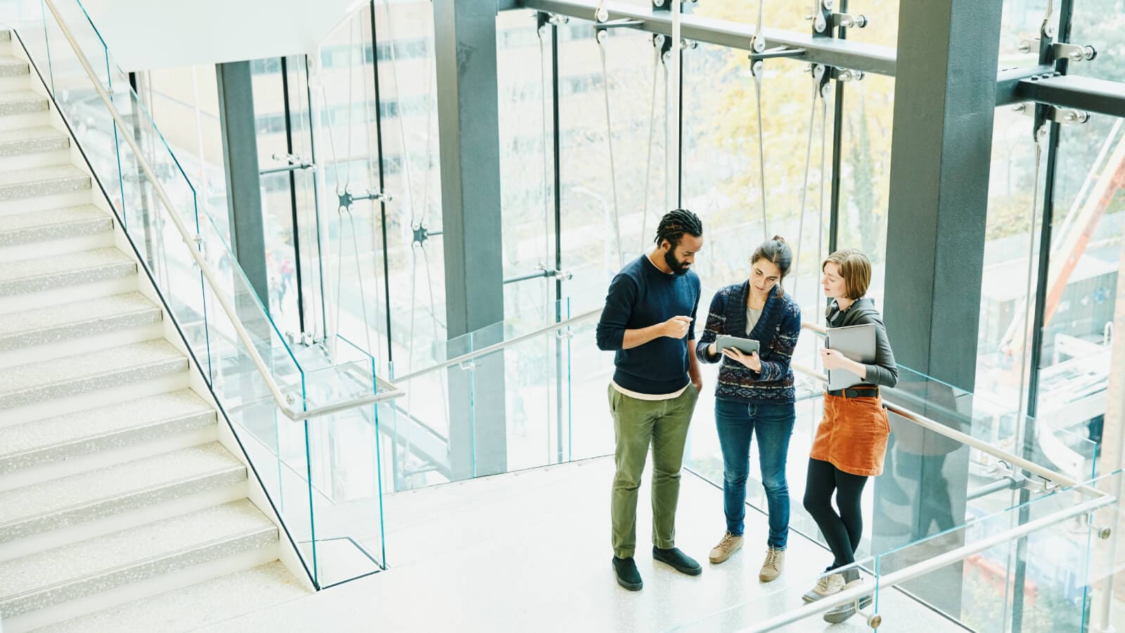 Coworkers discussing project on digital tablet on stairs of office building