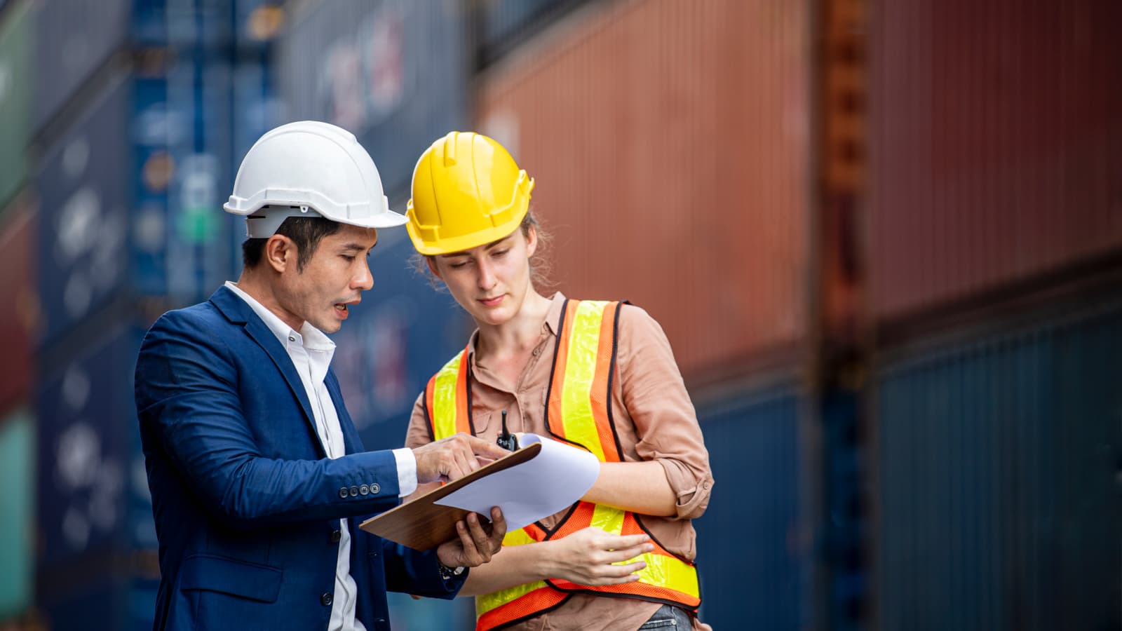 Shipper and inspector discuss together over a clipboard at commercial dock
