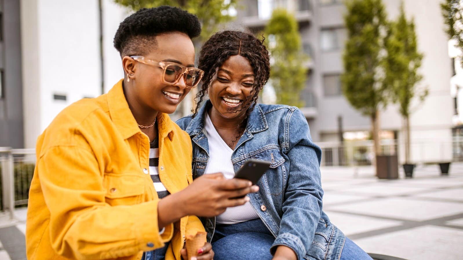 Two friends smiling whilst looking at a phone