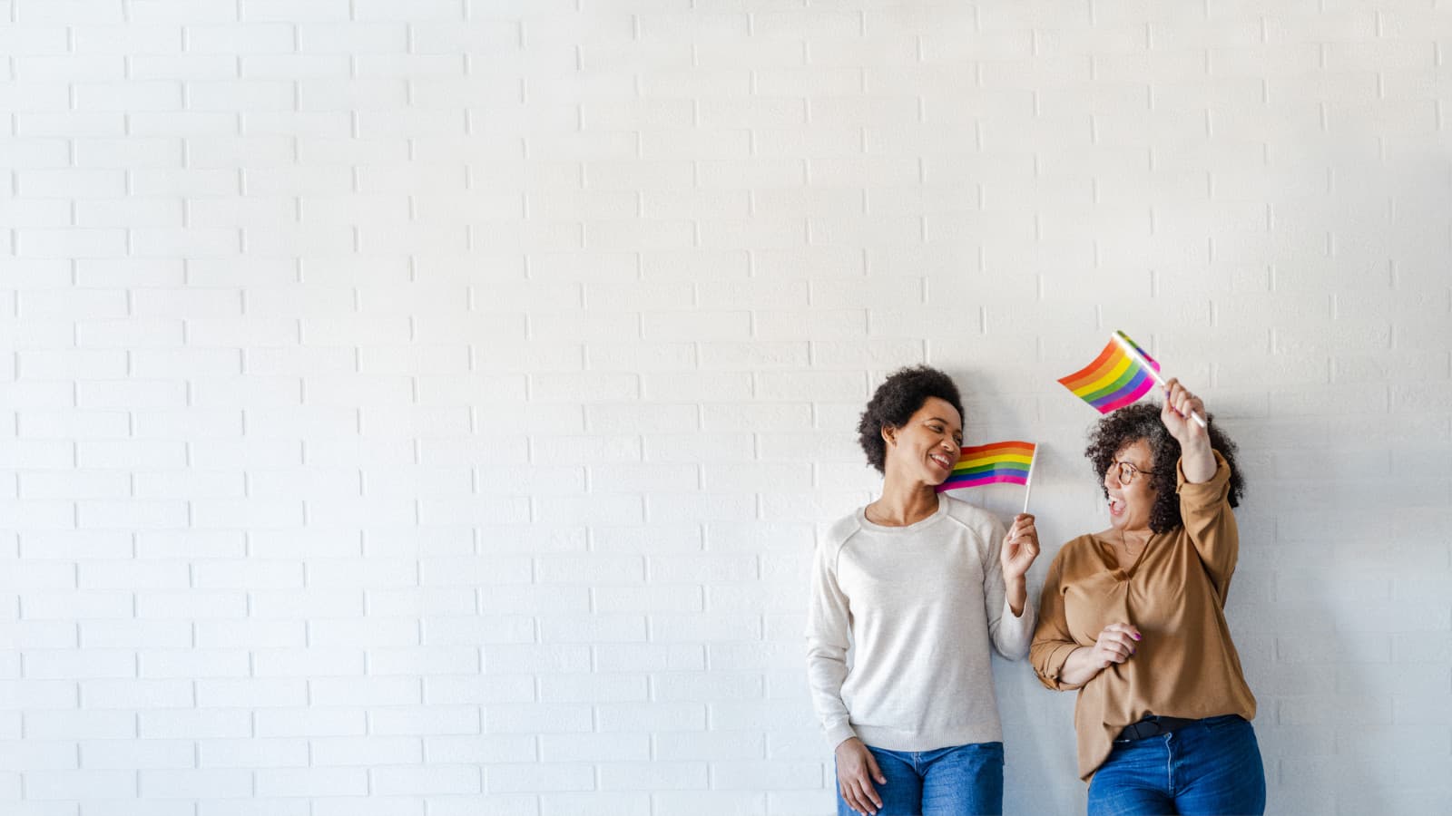 Lesbian couple waving with LGBTQIA flags