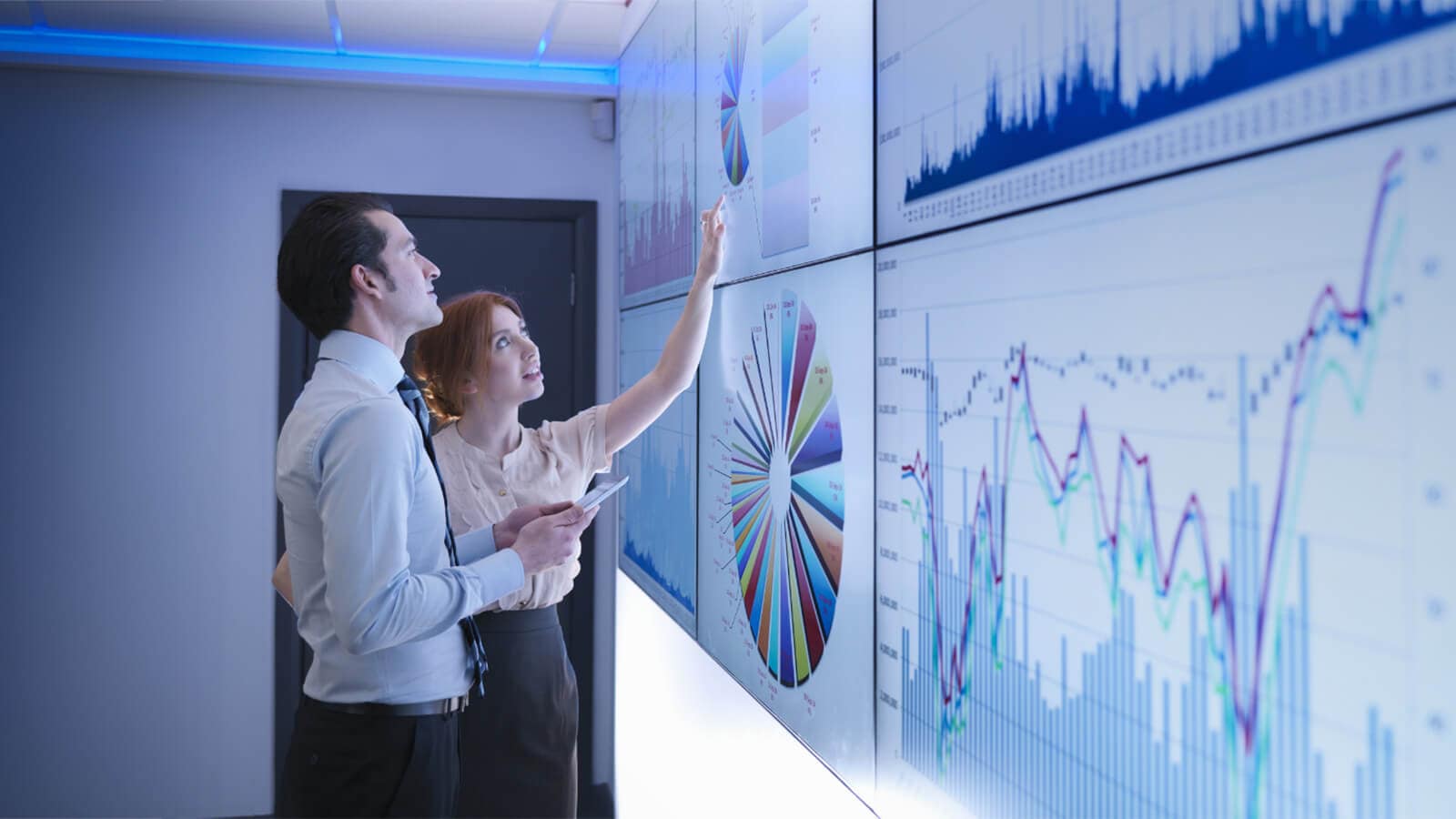 Business colleagues studying graphs on screen in meeting room