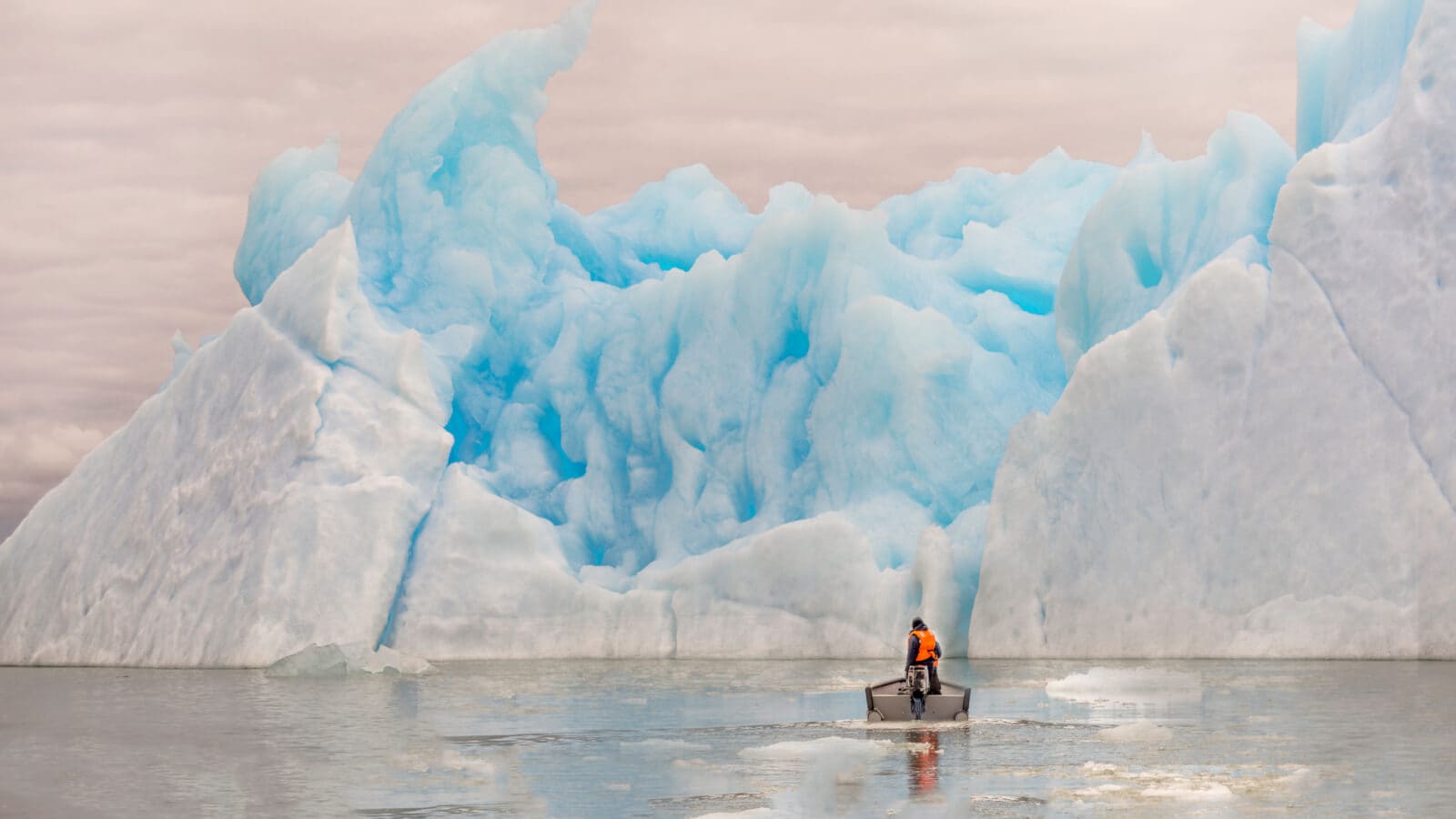 Man in boat near an iceberg in the sea