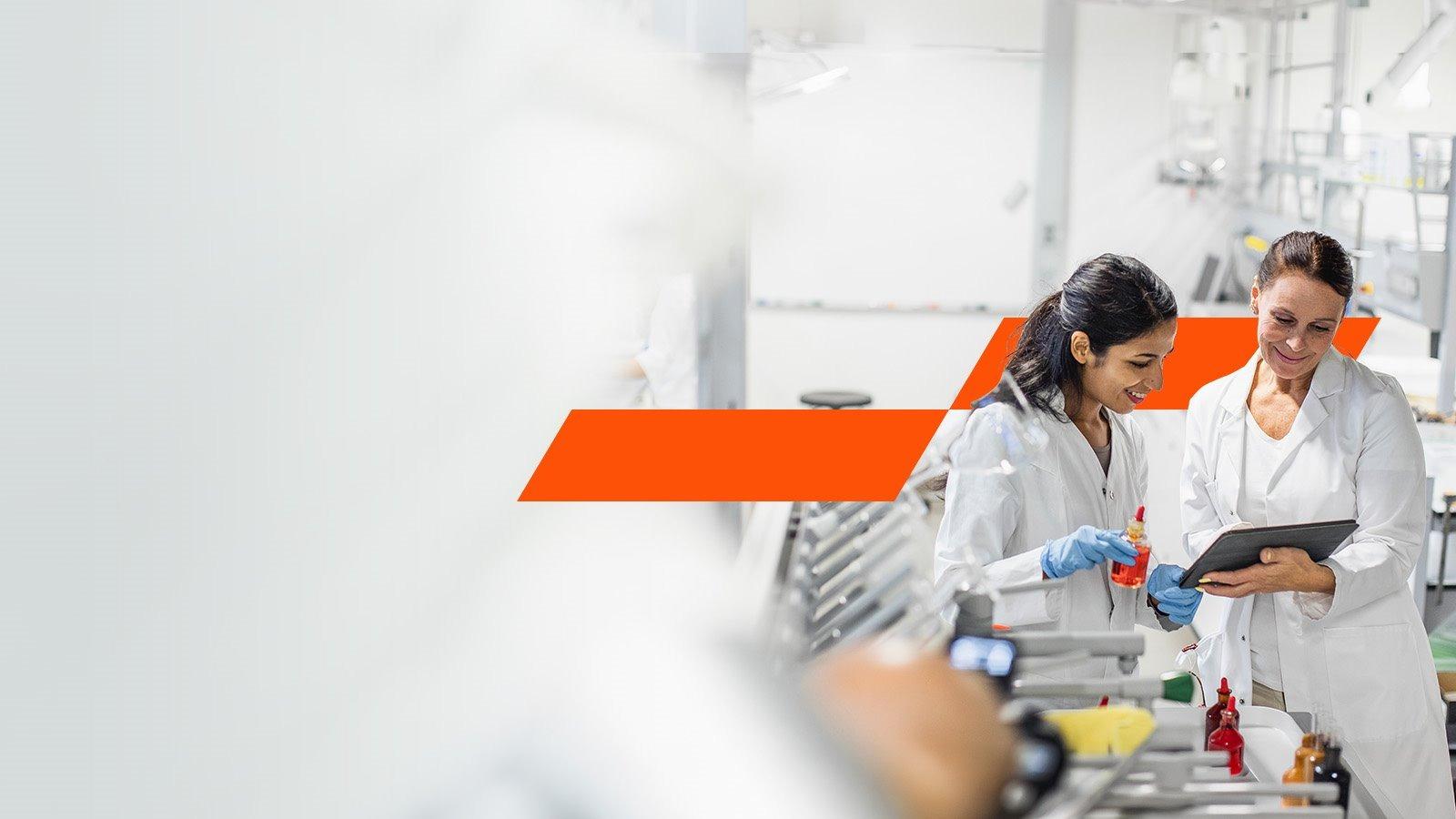 Two laboratory workers looking at tablet